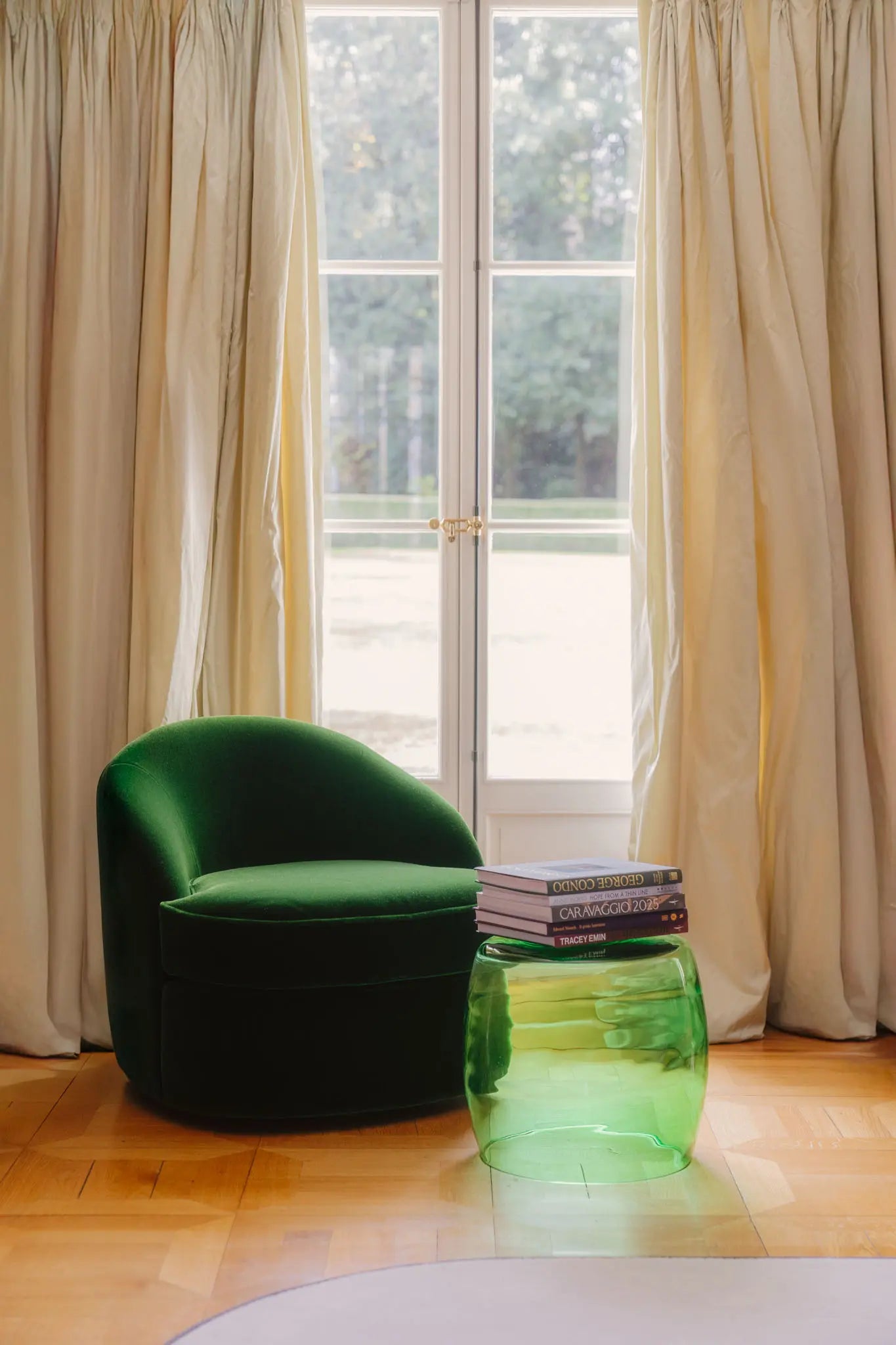 Tavolino Verde 40 Murano glass work placed in a soft-lit interior beside a green chair.