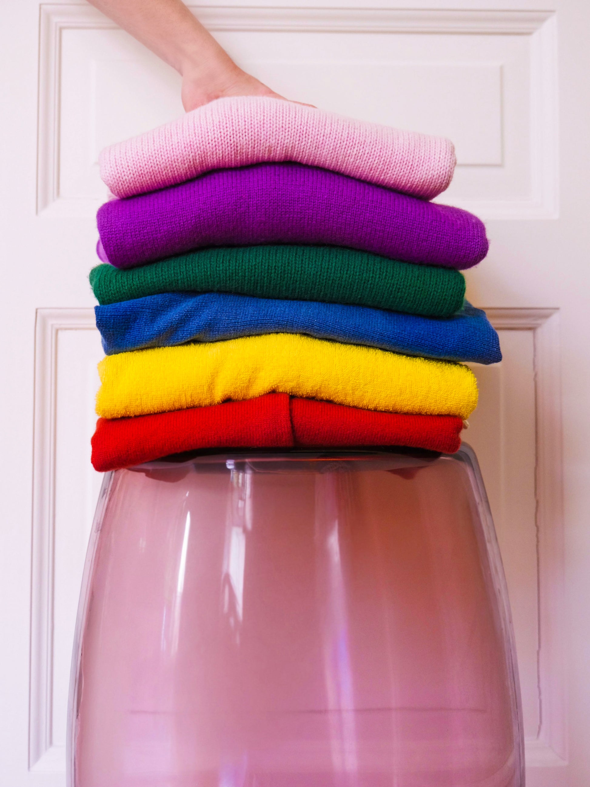 Tavolino Ametista 50 used as a sculptural base, amethyst Murano glass supporting stacked colourful knitwear in a contemporary interior.